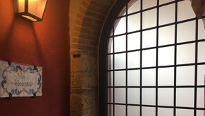 A room with a brick wall, a tiled floor, a frosted glass door, and a wall-mounted light fixture. - MontAlbano (Caserta)