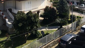 A residential area with houses featuring red-tiled roofs, a staircase leading to a balcony, and a view of hills in the background. - MontAlbano (Caserta)
