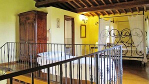 A room with a wooden ceiling, a bed with a white bedspread, a wooden wardrobe, and a metal railing. - Podere Caldaruccio La Pineta (Perugia)