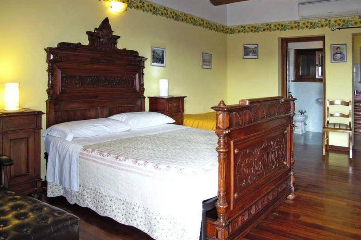 Un letto tradizionale in legno con una testiera alta, un comodino e un tavolino da notte.