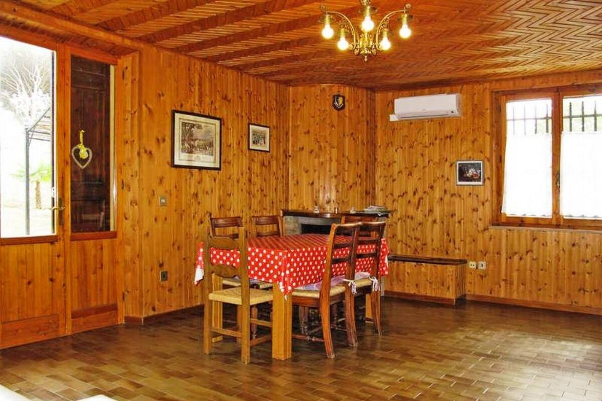 Una stanza con rivestimenti in legno, un tavolo da pranzo apparecchiato per quattro persone, un lampadario e quadri appesi alle pareti.