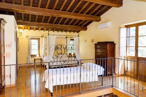 Un dormitorio con techo de madera, estructura de cama metálica, cómoda de madera y ventana con cortinas.