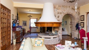 A cozy living room with a fireplace, wooden furniture, and a stone archway. - Podere Caldaruccio La Pineta (Perugia)