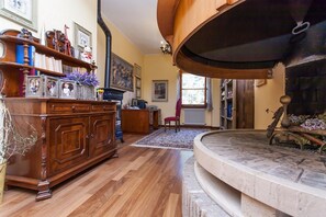 A spacious living room with a wooden cabinet, a fireplace, and a red chair. - Podere Caldaruccio La Pineta (Perugia)
