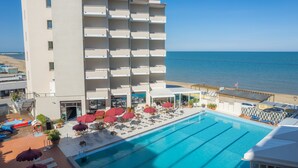 Un hotel con piscina, vista al mar y varios balcones.