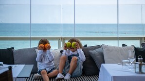 Dos niños sentados en un sofá con vista al océano.