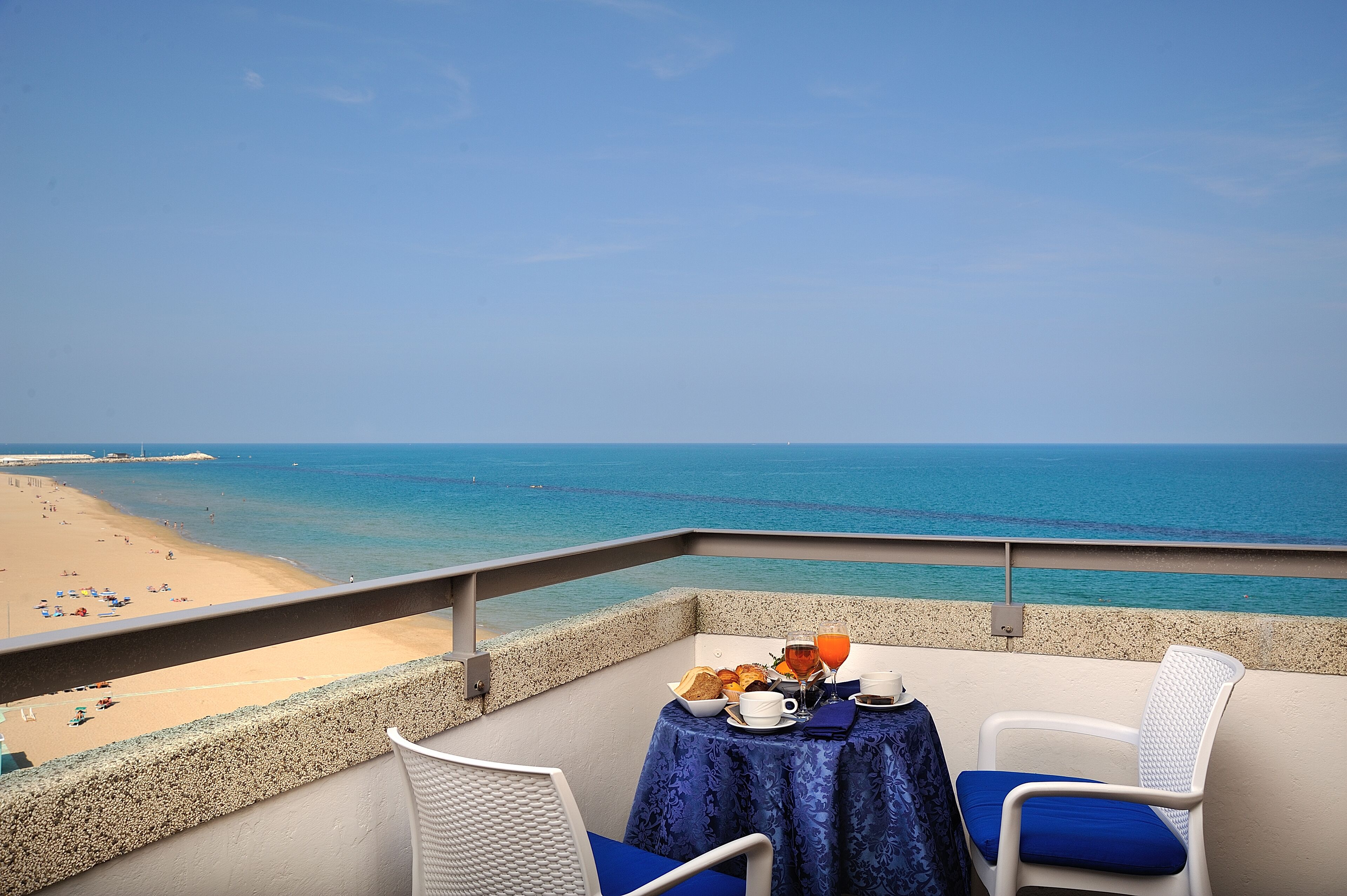Varanda com mesa posta para o café da manhã, com vista para uma praia.