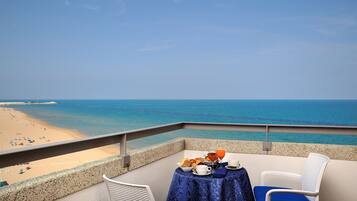 Varanda com mesa posta para o café da manhã, com vista para uma praia.
