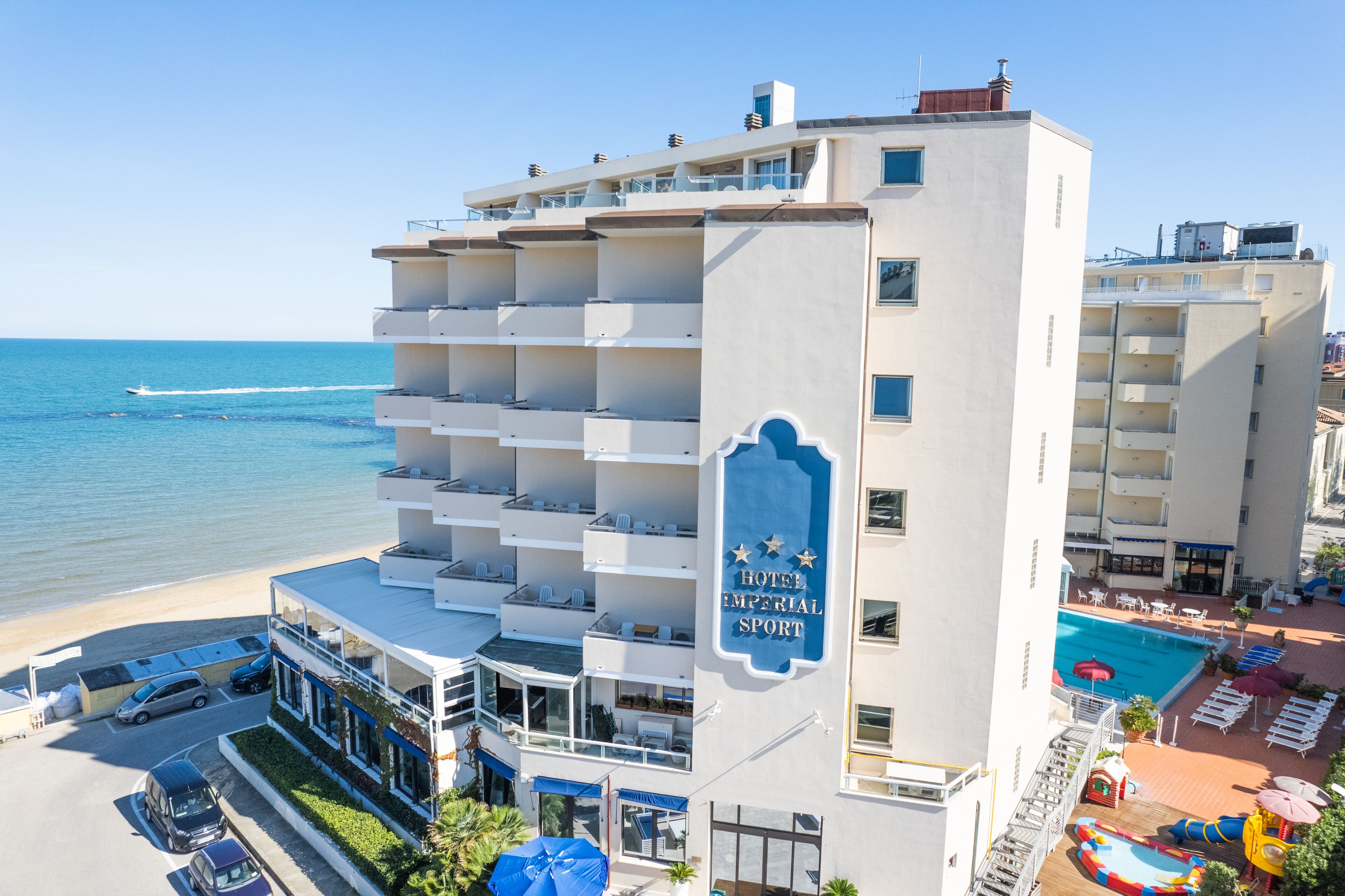 Ein Hotel mit mehreren Balkonen, einem Pool und Blick auf den Strand.