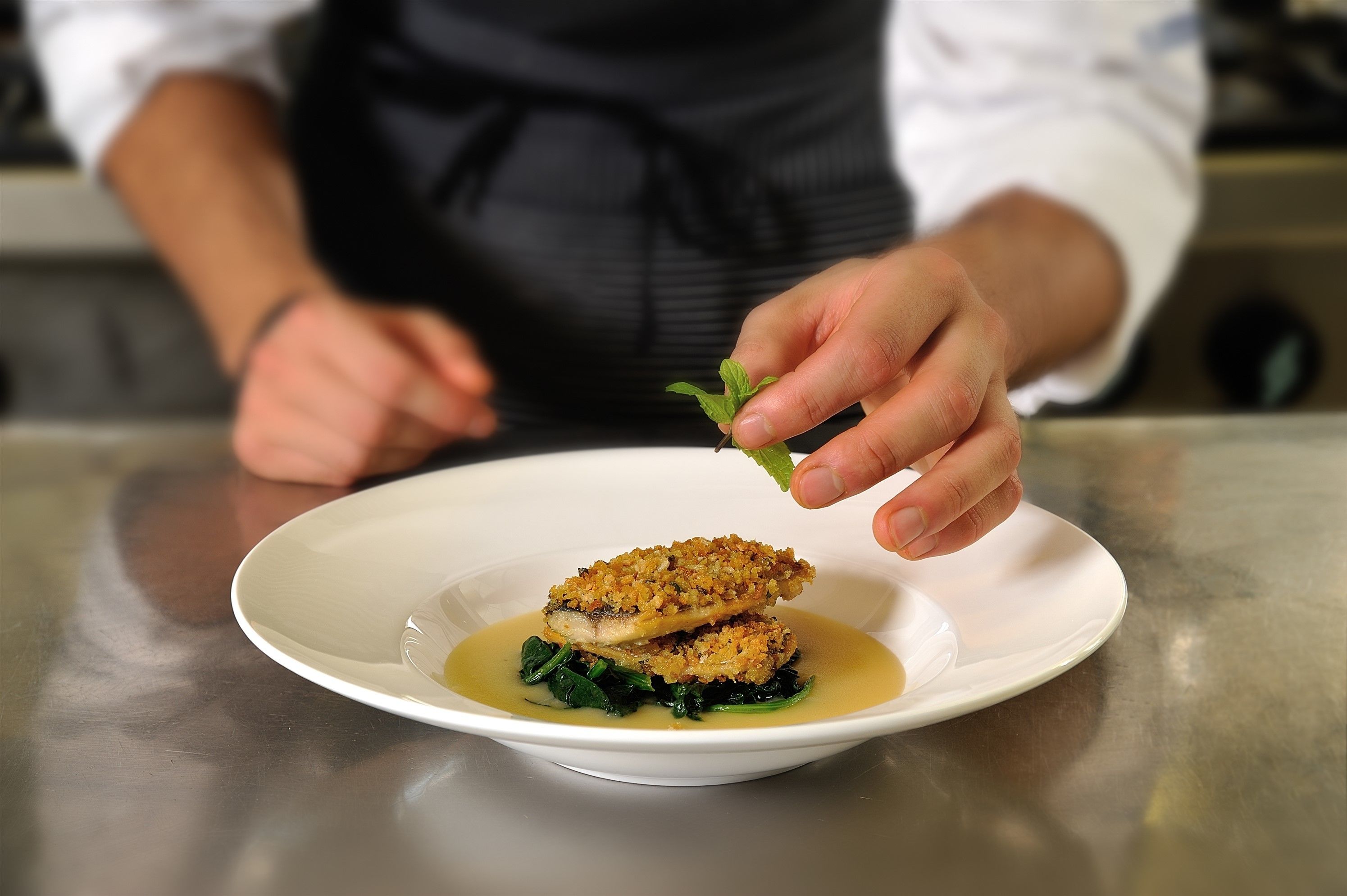 Un chef colocando un adorno en un plato.