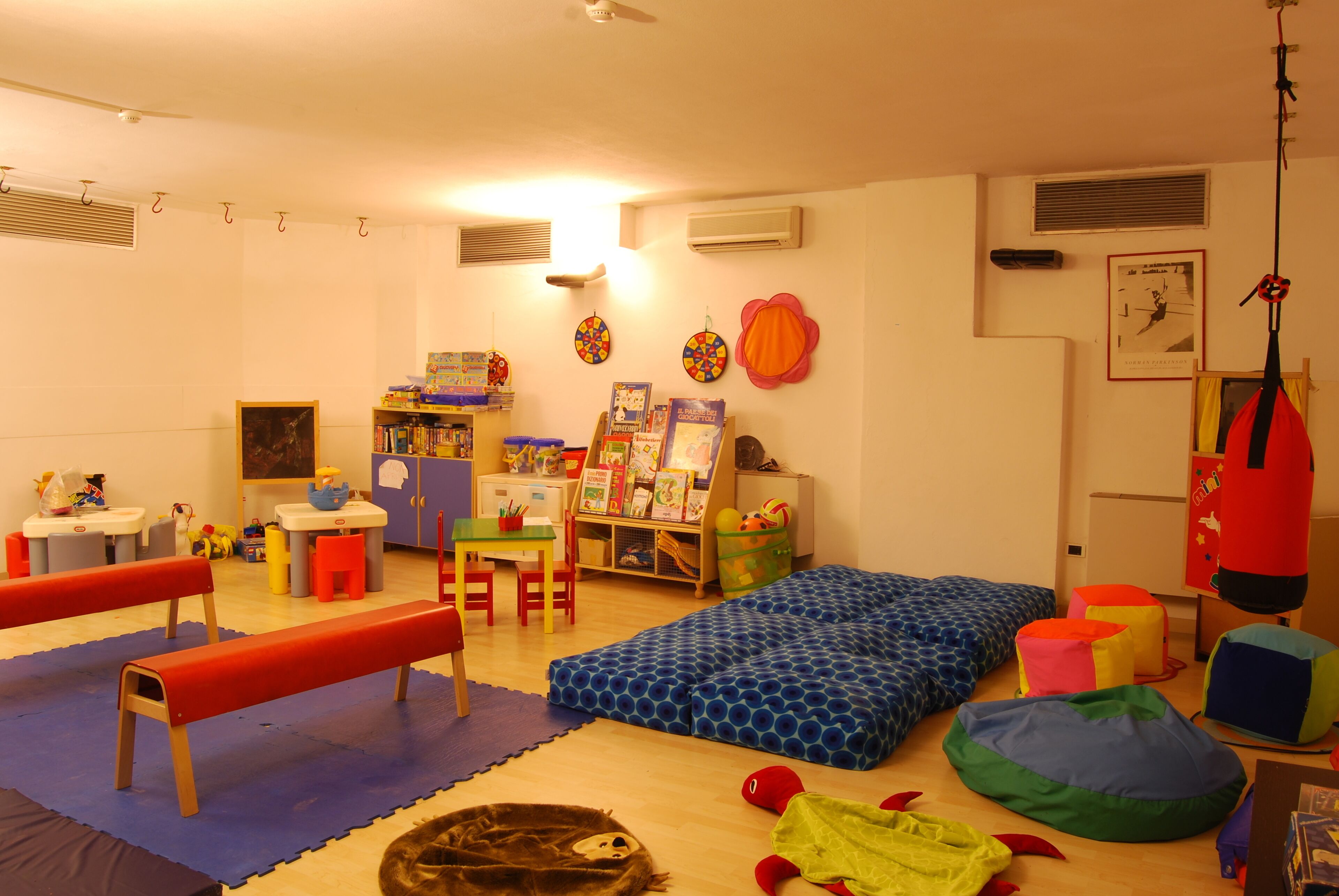 A children's playroom with a blue bean bag, a red bench, and a bookshelf filled with books.