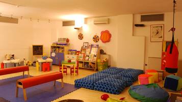 A children's playroom with a blue bean bag, a red bench, and a bookshelf filled with books.