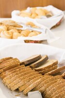 Una mesa de buffet con diversos alimentos, incluyendo pan y pasteles.