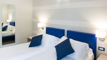 Una habitación de hotel con una cama grande, dos lámparas de noche, un espejo y una mesita de noche.