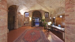 A spacious lobby with a high arched brick ceiling, a large ornate rug, and a reception desk with chairs. - Lo Spedalicchio (Bastia Umbra)