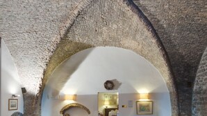 An interior with a vaulted brick ceiling, a patterned rug, and blue seating. - Lo Spedalicchio (Bastia Umbra)