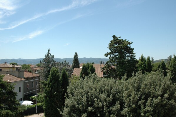 A residential area with houses, trees, and distant mountains under a clear sky.
