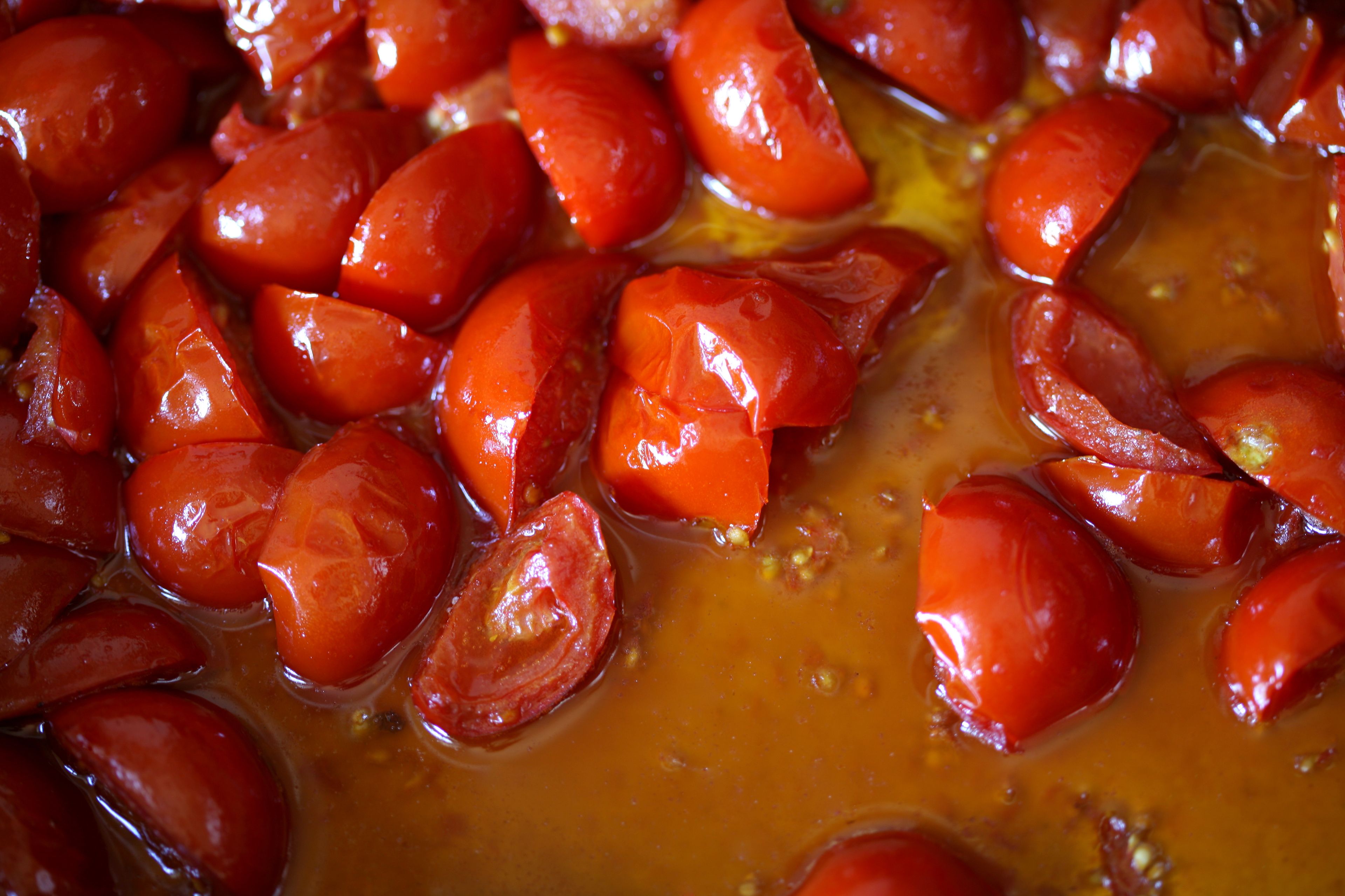 A close-up of red tomatoes in a sauce.