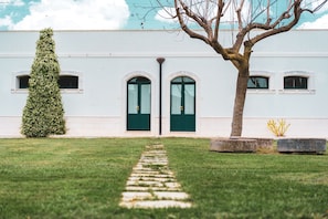 Un edificio con fachada blanca, una puerta doble central y un camino empedrado que conduce a él.