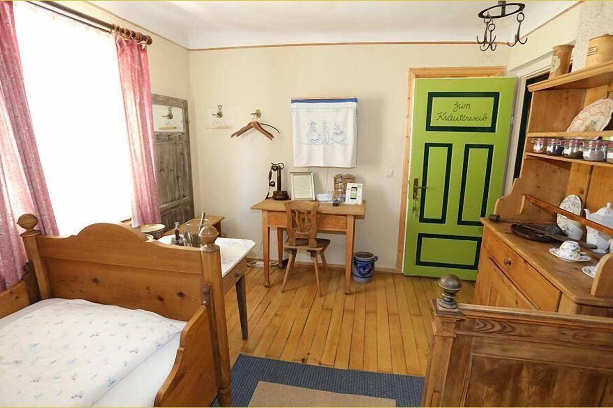 Een knus slaapkamer met een houten bed, een bureau en een groene deur.