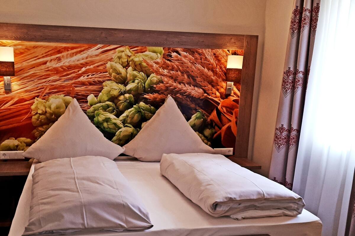 Een hotelkamer met een bed, kussens en een hoofdeinde met een decoratieve wand.