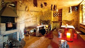 A rustic stone interior with a fireplace, wooden furniture, and stone walls. - Hotel Dachsenfranz (Zuzenhausen)