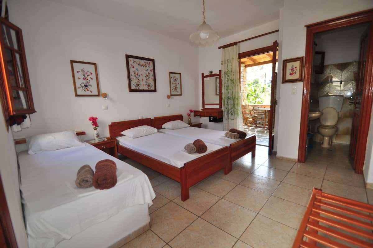 A hotel room with two beds, a wooden headboard, a mirror, and a bathroom visible through an open door.