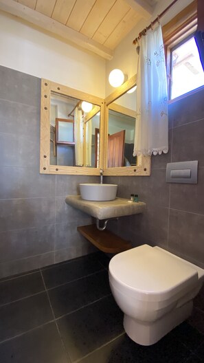 Une salle de bain avec un meuble-lavabo en bois, un lavabo blanc, des toilettes et un miroir avec un cadre en bois.
