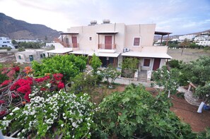Un bâtiment à deux étages doté d’un balcon, entouré d’une végétation luxuriante et de plantes en fleurs.