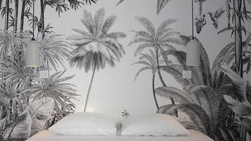 Une chambre à coucher ornée d’une fresque représentant des plantes et des oiseaux tropicaux, avec un lit recouvert de linge de lit blanc et des lampes suspendues.