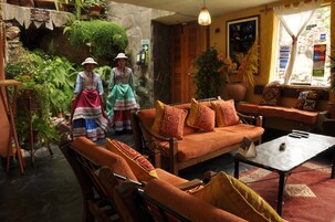 A cozy interior with a sofa, chairs, and a coffee table. There are potted plants and a stone wall.