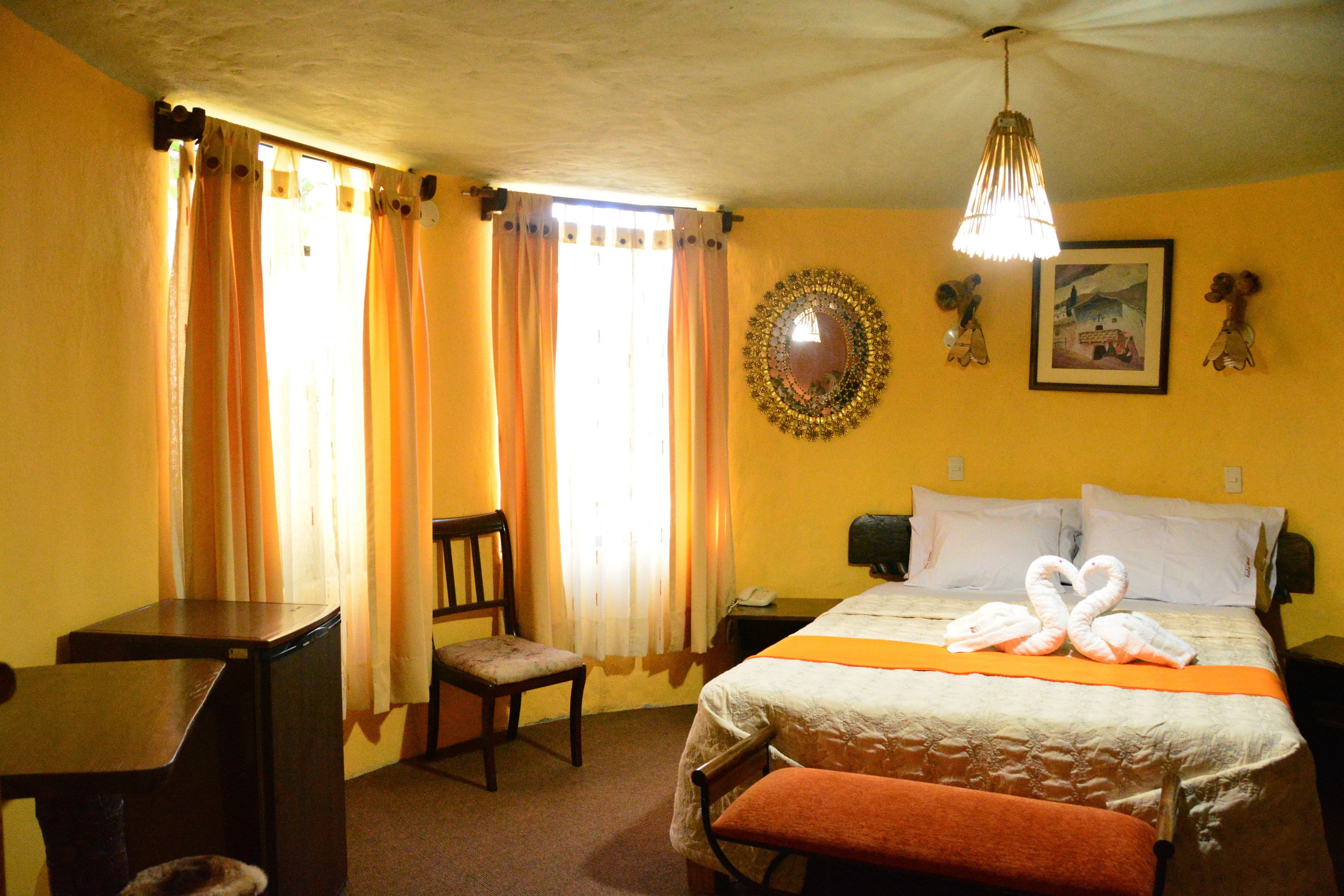 Une chambre d’hôtel avec un lit, un bureau, une chaise et une table de chevet.