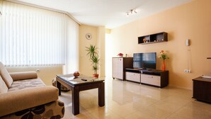 A living room with a sofa, a coffee table, a TV, a cabinet, and a potted plant. - Bright House (Plovdiv)