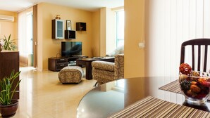 A modern living room with a flat-screen TV, comfortable seating, and a dining area with a glass table. - Bright House (Plovdiv)