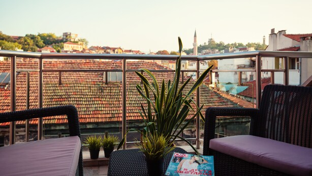 A balcony with wicker furniture, potted plants, and a magazine. - Bright House (Plovdiv)