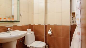 Un baño con lavamanos, inodoro y espejo.