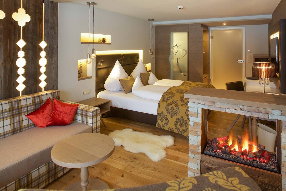Une chambre d’hôtel moderne équipée d’un lit, d’un canapé, d’une petite table et d’une cheminée.