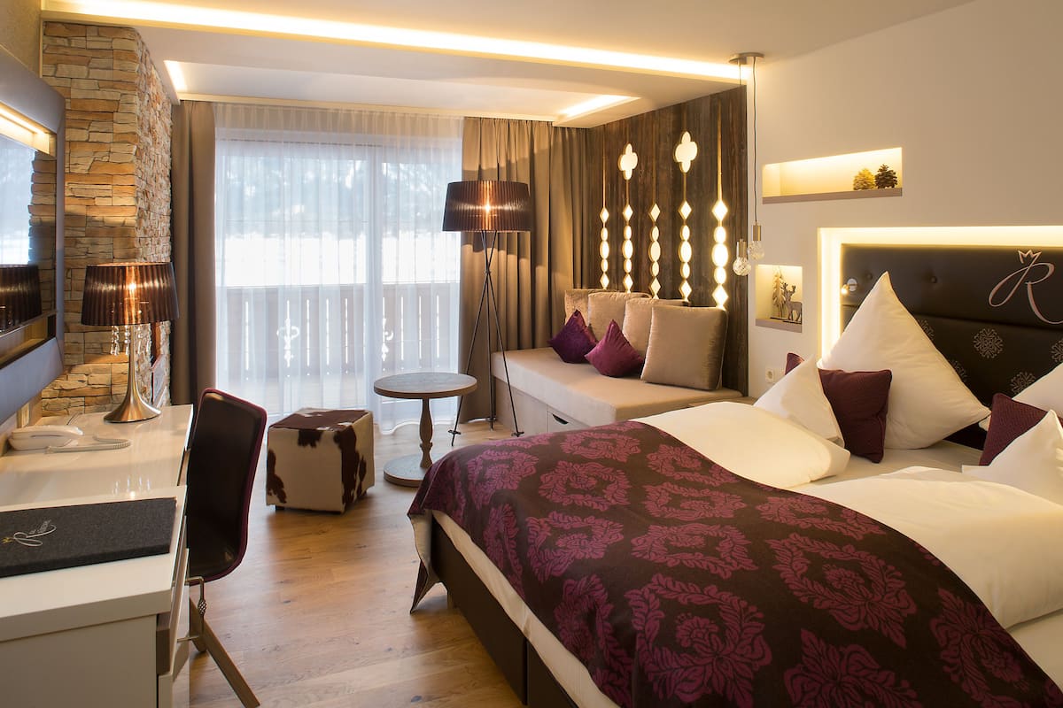 Une chambre d’hôtel moderne dotée d’un grand lit, d’un canapé, d’un bureau et d’un balcon avec des rideaux.