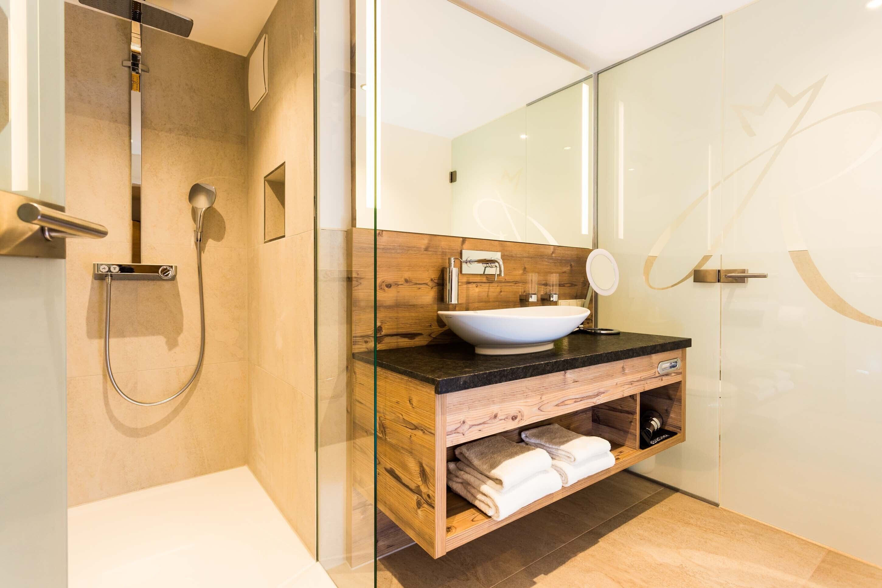 Une salle de bain moderne avec une douche à parois de verre, un meuble-lavabo en bois avec un lavabo blanc et un grand miroir.