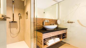 Une salle de bain moderne avec une douche à parois de verre, un meuble-lavabo en bois avec un lavabo blanc et un grand miroir.