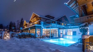 A snow-covered landscape with a wooden house featuring large windows and a swimming pool. - Das Rübezahl – Romantic Hideaway & Boutique Spa (Schwangau)