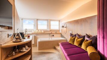 A modern bathroom with a bathtub, vanity, and a purple sofa with cushions.