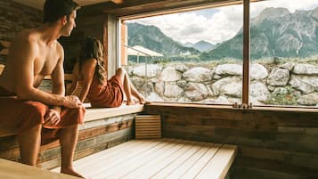 A wooden cabin with a stone wall and a window overlooking a mountainous landscape.