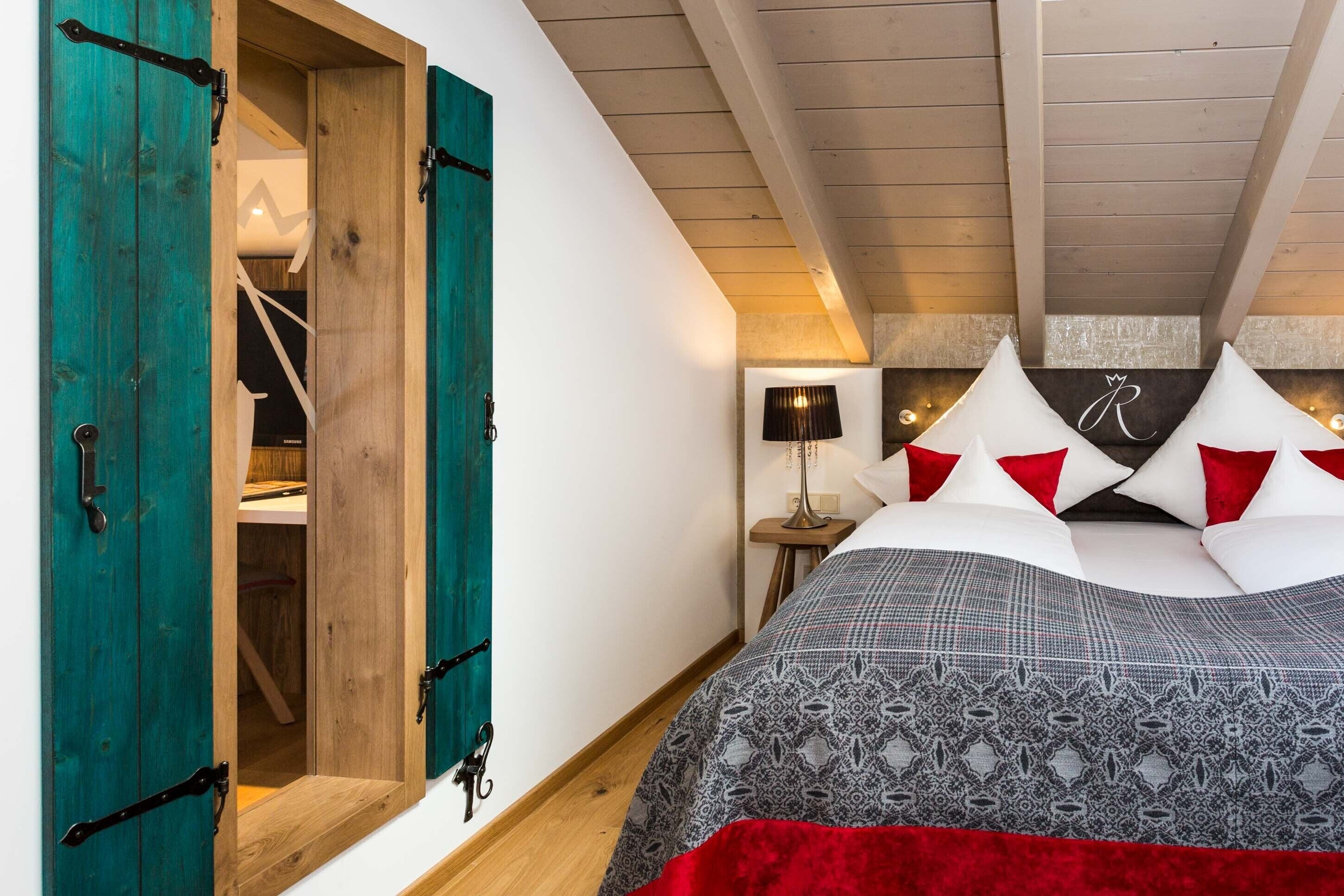 Un dormitorio con una cama, puertas de madera color turquesa, una mesita de noche y una lámpara.