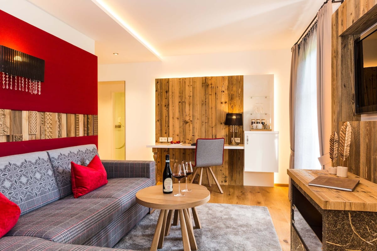 Un salon moderne avec un canapé, une table ronde en bois et un coin repas agrémenté d’un mur en bois et d’une chaise.