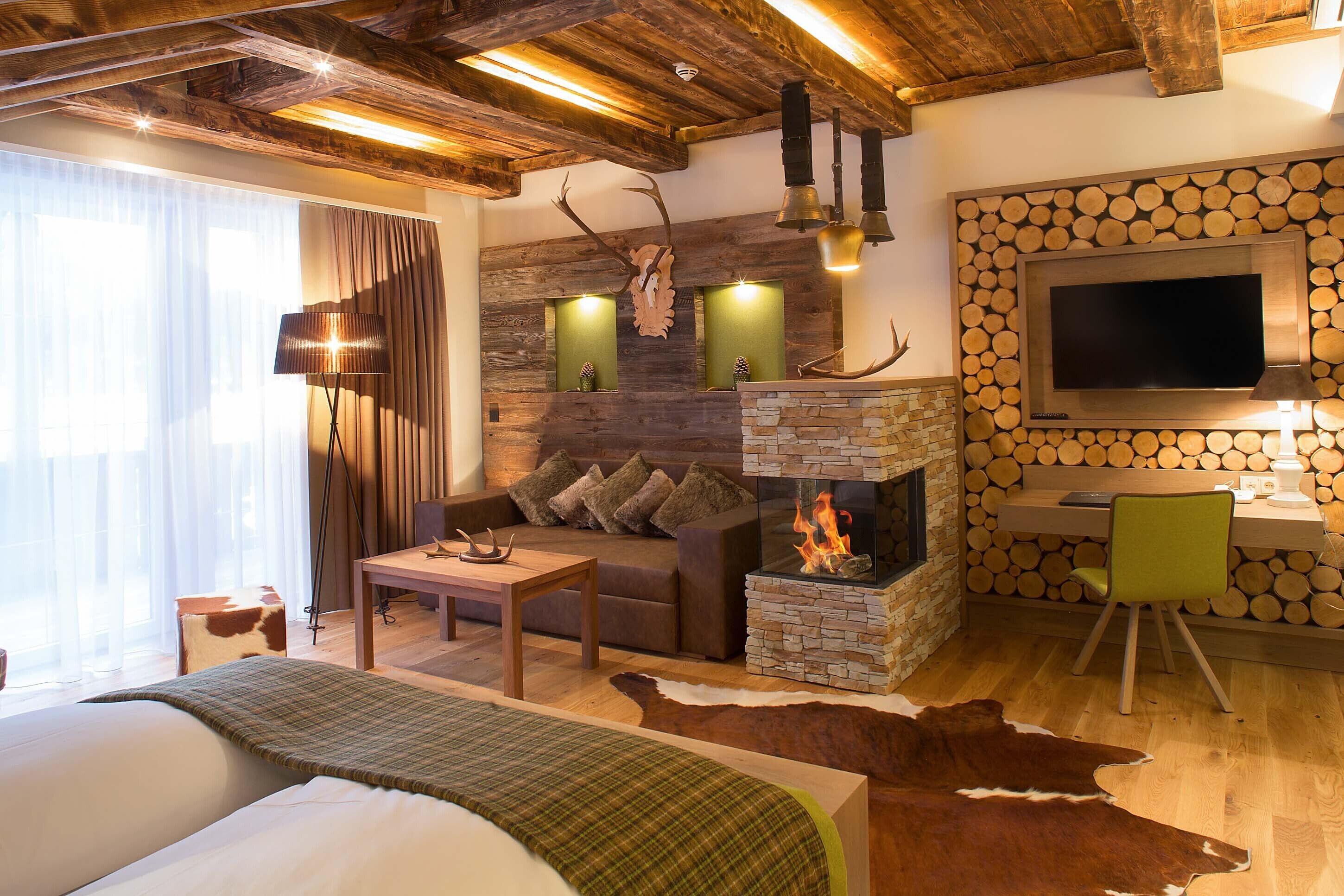 A cozy room with a fireplace, a sofa, a desk, and a television.