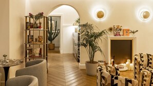 A cozy living room with a fireplace, a bookshelf, and a potted plant. - Nerva Boutique Hotel (Rome)