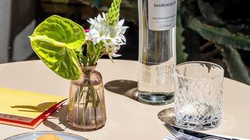 A table with a bottle of water, a glass, a cup, a plate with cookies, a spoon, a napkin, and a book.