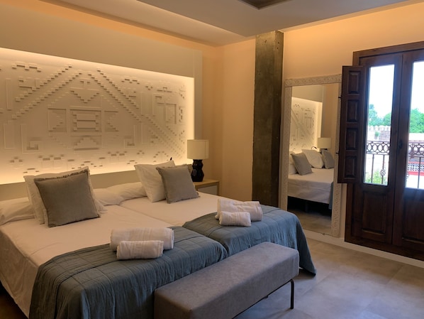 A modern hotel room with a large bed, a bench, and a decorative wall panel. - Hacienda Del Cardenal (Toledo)