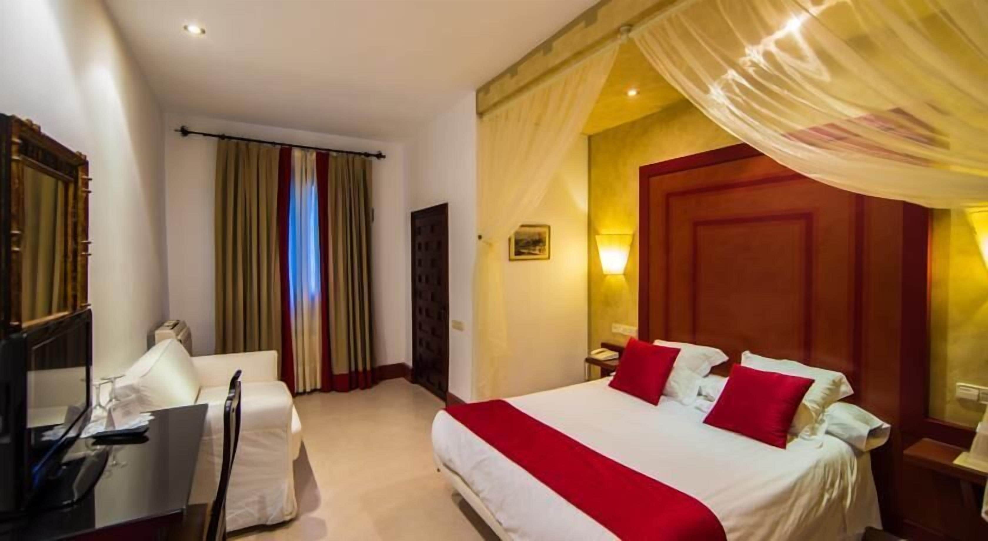 Quarto de hotel com cama, escrivaninha e cadeira.